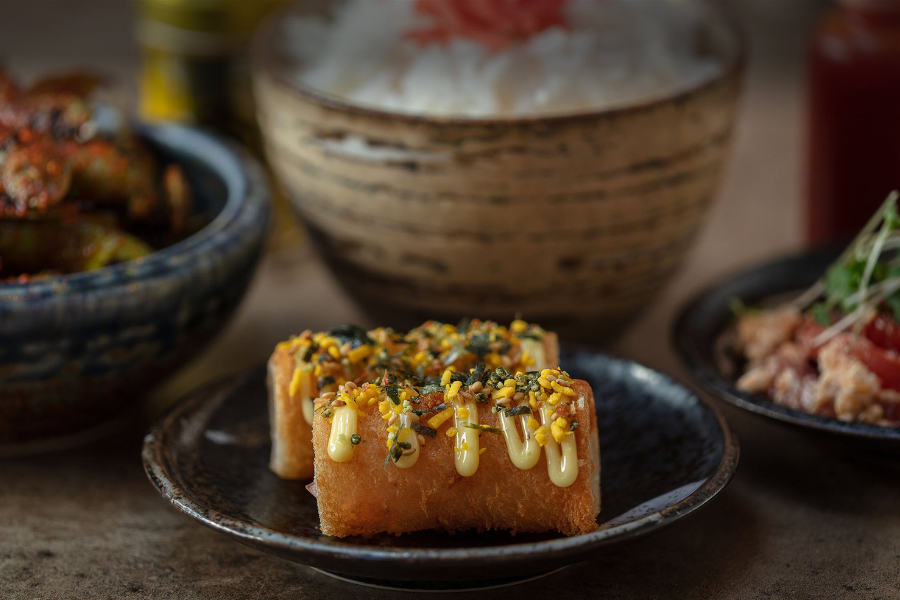 Prawn toast with a yellow sauce and green garnish on a dark plate at Kushi-Ya in Nottingham